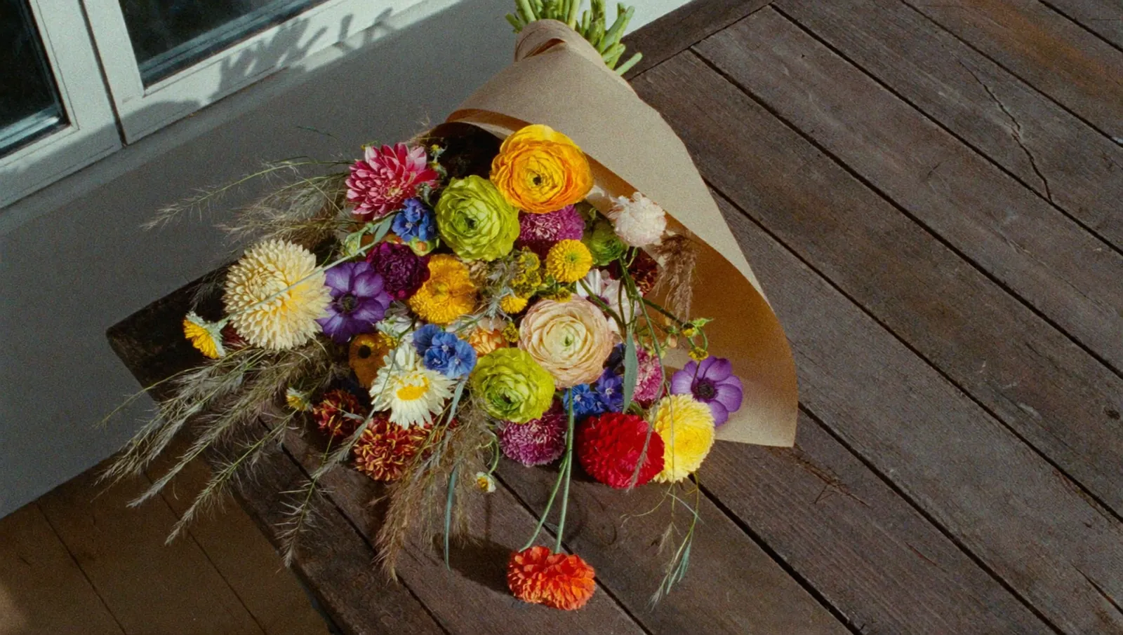 Bouquet champêtre coloré dans du kraft sur une table en bois, image d’ambiance générée